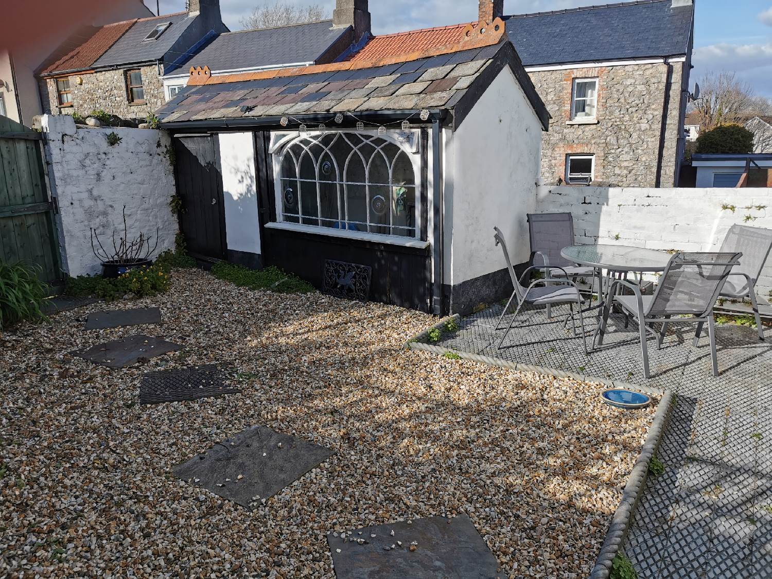 Pilton House Gower's Courtyard Garden with dining table and chairs and the Garden Studio